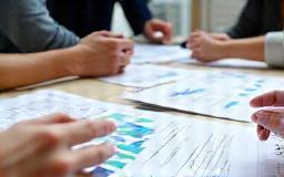 People reviewing charts and notes in a meeting, planning a campaign